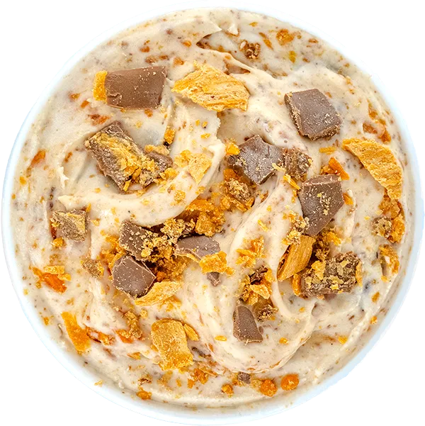 Creamy ice cream with chocolate and caramel chunks in a bowl. Delicious dessert topped with crunchy pieces.